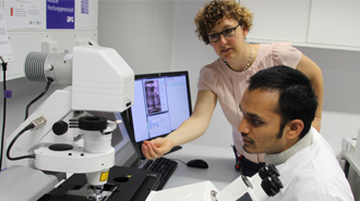 Two persons working with a microscope