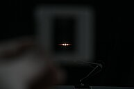 This image shows a mostly black background with two bright points of white light near the center. The light sources are very close to each other, and each emits several thin, straight lines spreading horizontally, which makes a star-like effect. Around these lines, there are faint colored strips—mainly green and red—which create a subtle rainbow effect extending from the two bright points. The rest of the image is dark, and the lights stand out sharply in the center.