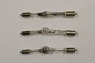 Photo of three used mercury arch lamp light bulbs. The glass of the bulbs has visible distortions and spots of vaporized mercury.