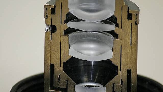 Photo of a microscope objective cut in half. The arrangement of the various lenses inside the objective is visible.